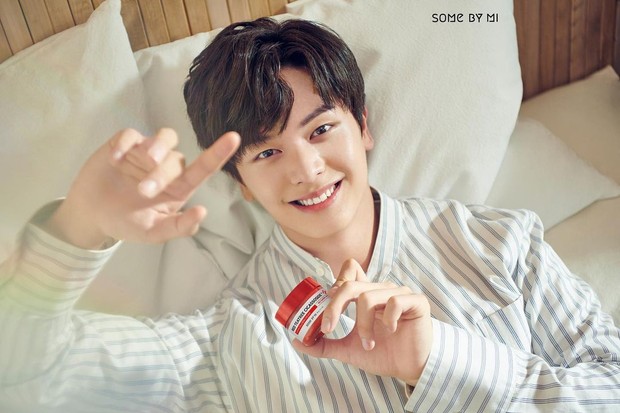 Seorang pria dengan wajah bersih dan segar tersenyum memegang produk skincare sebagai cara agar tetap awet muda